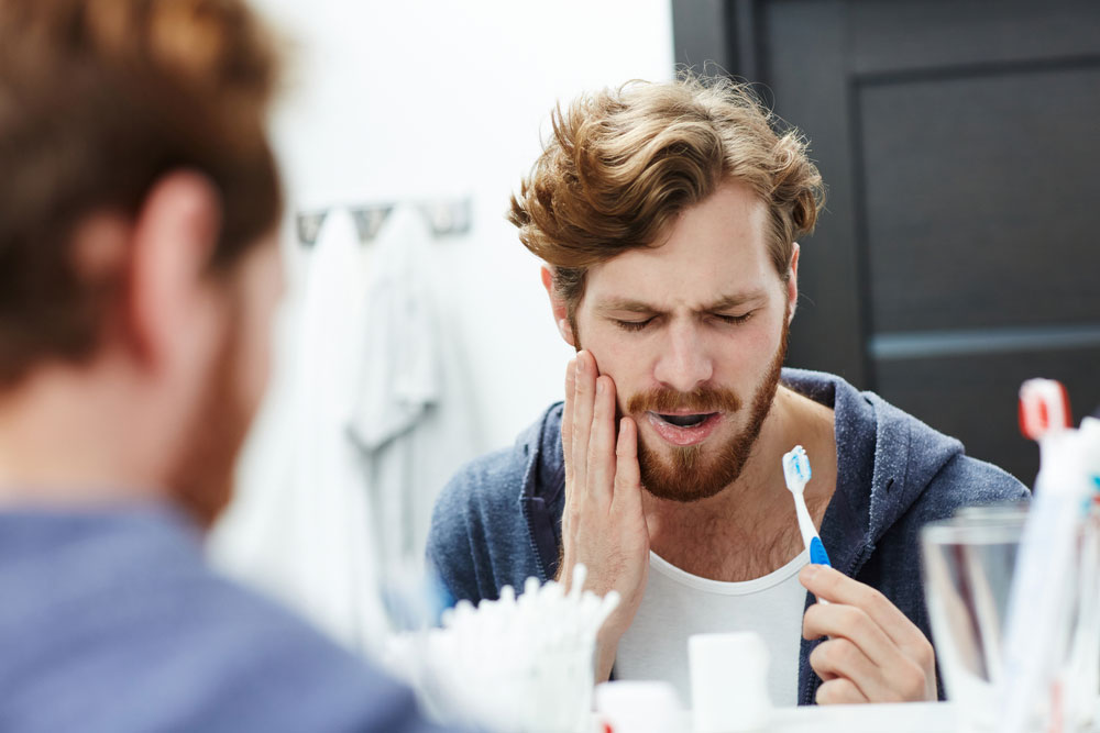 a man holding his jaw while brushing